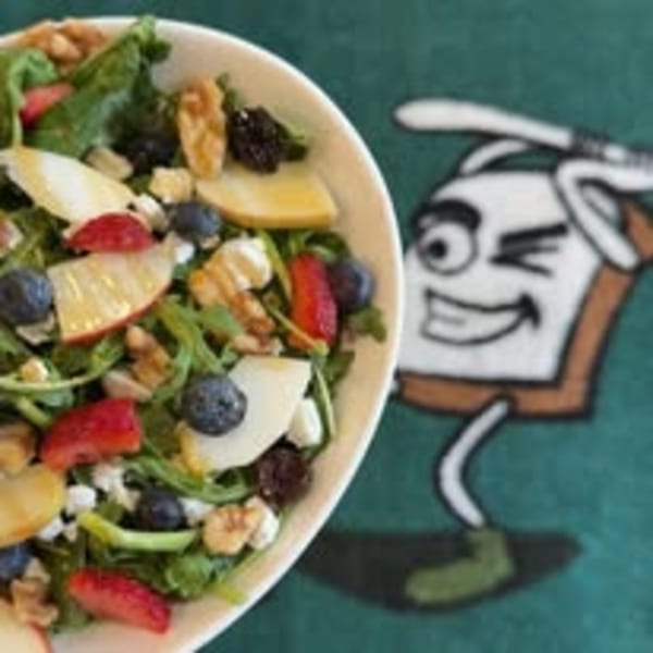 A fresh salad with mixed greens, apples, blueberries, strawberries, walnuts, and feta cheese.